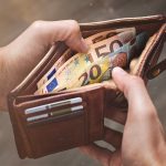 Hands opening a leather wallet with Euro banknotes inside