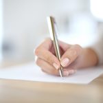 Closeup of woman’s hand writing on paper