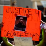 Miami Downtown, FL, USA – MAY 31, 2020: George Floyd death: people are protesting and rioting. Justice for George Floyd poster. People took to the streets against cruelty.